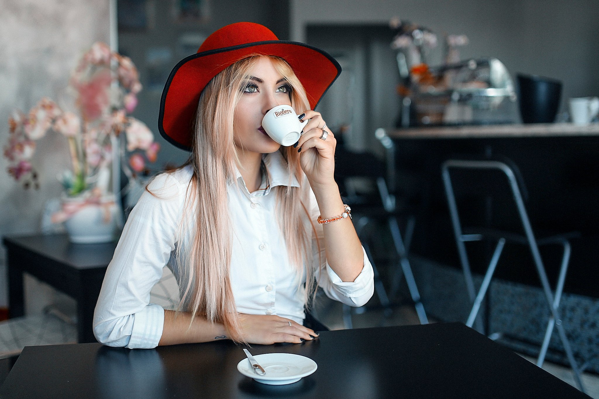 Девушка в шляпе пьет кофе